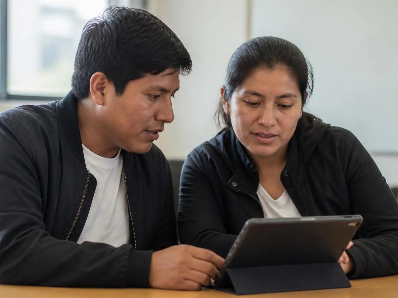 Dos personas revisando notas en una tablet sobre la mesa